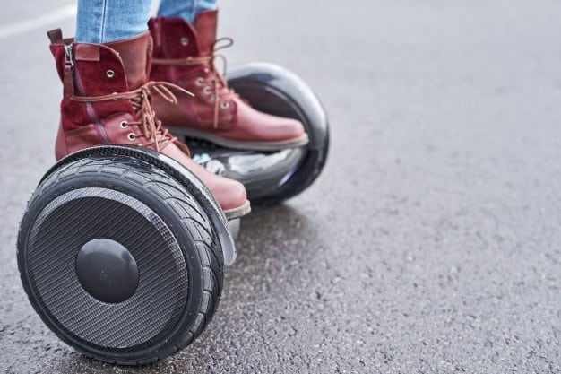 close-up-woman-using-hoverboard-onsphalt-road-feet-electrical-scooter-outdoor_77190-2994