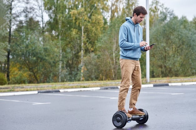 man-riding-hoverboard-using-smartphone-outdoor_77190-3413